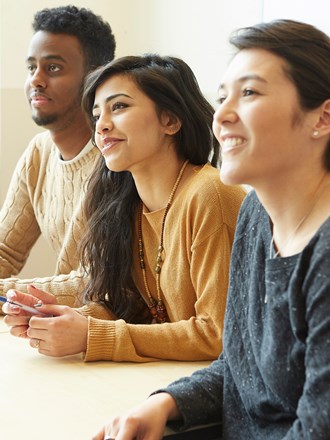 A group of smiling students smiling in a lecture A group of smiling students smiling in a lecture